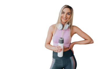 Cheerful blonde caucasian young girl in sportswear holds bottle of water looks at camera toothy smiles stands over transparent background. Healthy lifestyle, sporty women. woman at break of exercise
