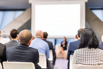 Business and entrepreneurship symposium. Female speaker giving a talk at business meeting. Audience...