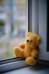 Bear childrens soft toy sitting edge an open window.Concept accidents with children.