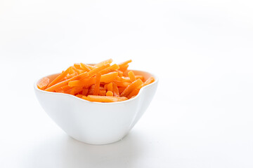 Frozen cut orange carrot in white bowl on white. Healthy food. Copy space. Horizontal format.