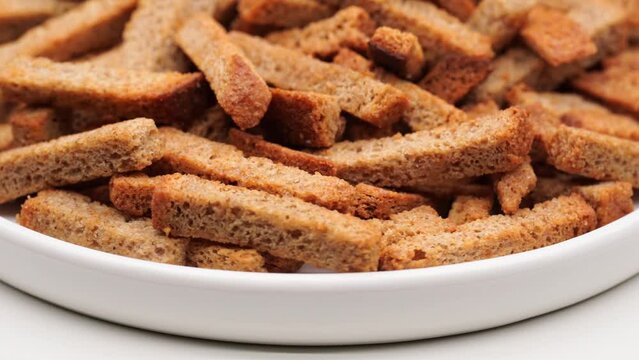 Crispy toasted bread croutons. A pile of hard rusks from dark dry bread close up. Snack for beer. Rye crackers. Snacks rye crackers in a strip. Crouton or brown roasted tostes rotating. 