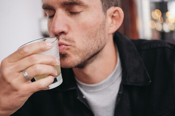 A man kissing a glass with a drink