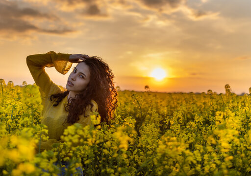 Pretty girl in rapeseed field with yellow flowers