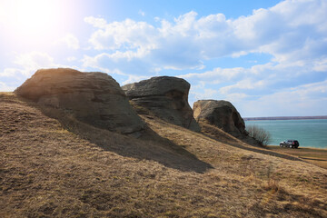 Car at the shore of the lake near the old rocks