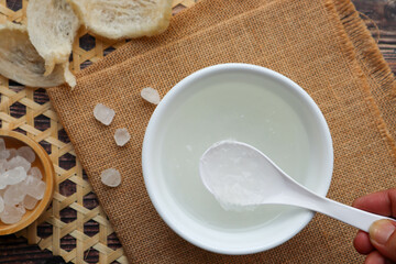 Edible Bird's nest soup with rock sugar in white bowl at top view on wood table 