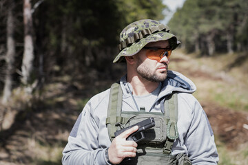 A private military man with a pistol in his hand in the forest.