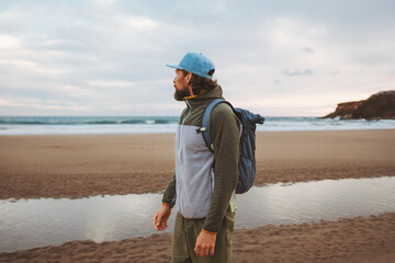 Man traveling solo walking on the beach with backpack healthy lifestyle active summer vacations...