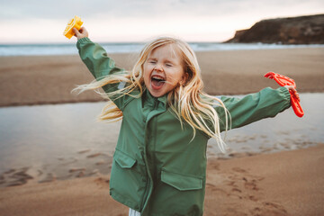 Child girl happy laughing playing outdoor family lifestyle vacations emotional kid smiling walking with toys on the beach - 598601542