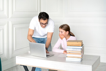 Father and daughter studying together online at home. He explaining lesson and she listening him...