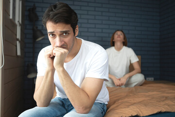 Frustrated and depressed man sitting on the edge of the bed after conflict with his wife because of his erectile dysfunction problem