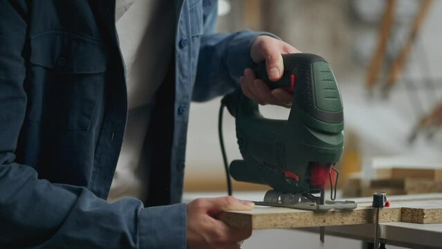 Carpenter, Active caucasian woman Cutting with a power tool with a jigsaw In a new private house, Active young worker assembling new furniture, Standing in front of a work surface, work tool
