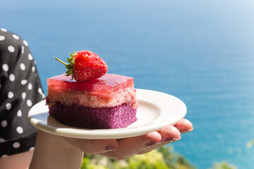 Nice little dessert in nature, a cake on a white dish in a female hand.
