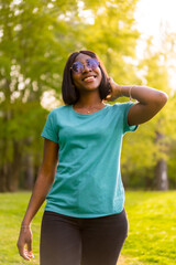 Green Summer: Portrait of a Young Black Tourist Woman with Sunglasses Enjoying the Outdoors at Sunset in the Forest
