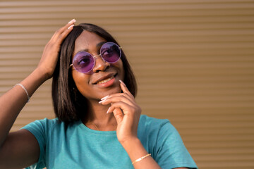 Sunny Days and Good Vibes: A Portrait of a Young Black Female Tourist Wearing Green Tee and Shades Against a Brown Wall