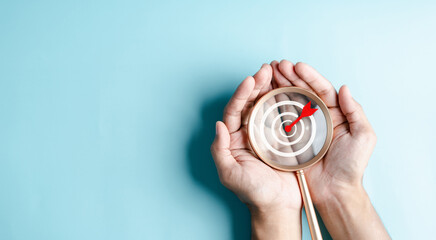 Business hands holding target icon on magnifier, dartboard and arrow for creative and set up...
