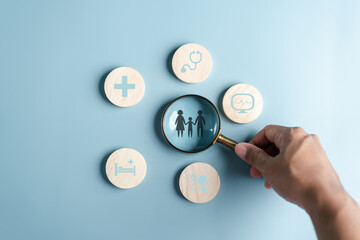 Health and Life insurance of protect family concept. Magnifier focus to family icon with healthcare medical icon on wooden cube block, health and access to welfare health concept