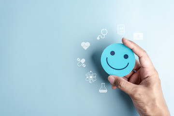 Fototapeta Hands holding blue happy smile face for medical care concept. mental health positive thinking. obraz