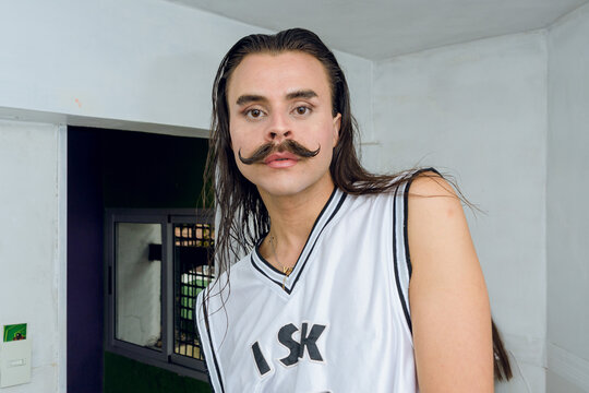 gender non-binary latino person looking at the camera after combing her hair and putting on makeup.