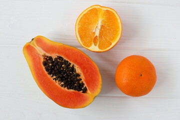 Papaya and orange tropical fruits on white wooden table