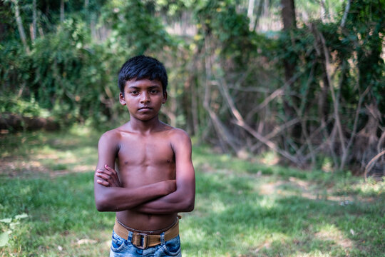 South asian shirtless young boy standing in nature looking confident, copy space for advertisement in right side 