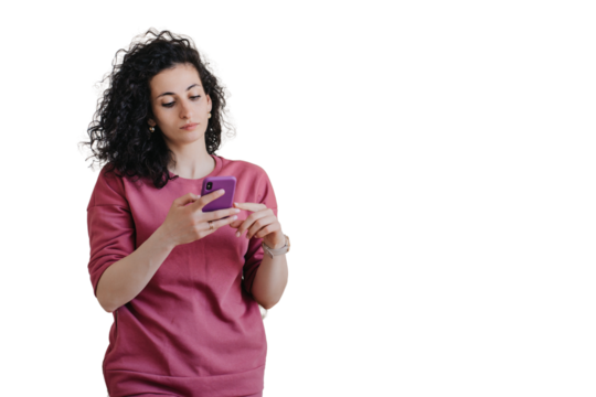 Upset young curly woman in violet sweater holds phone looks at screen with frustrated face expression against transparent background. People emotions. Troubles, fatigue, exhaustion. Disappointed woman