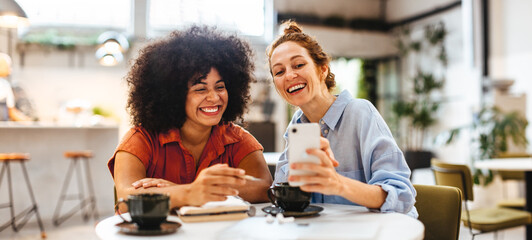 Female remote workers video calling clients on a mobile phone