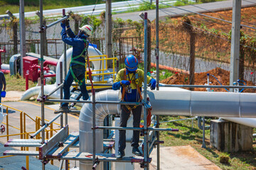 Architect on site construction workers on a scaffold pipeline