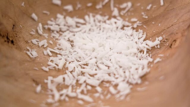 Dietary grated coconut flake ingredient in a wooden bowl closeup