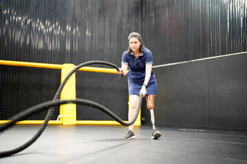 Portrait of disabled athlete woman with prosthetic leg in fitness gym