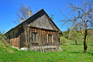 Obraz premium Old abandoned village buildings on a spring day on tree and blue sky background, rural landscape, Low Beskids, Poland
