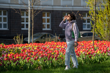 A woman is standing in the city by a large tulip bed
