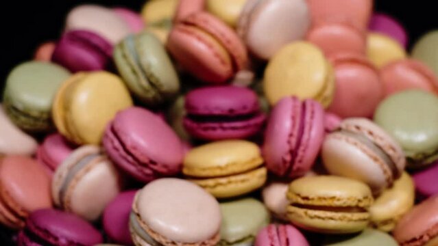 Focusing on macaron cookies. Traditional french desserts from almond dough. Slow motion of out of focus colourful sweet macaron cakes spinning on a plate. French cuisine or sweets concept.