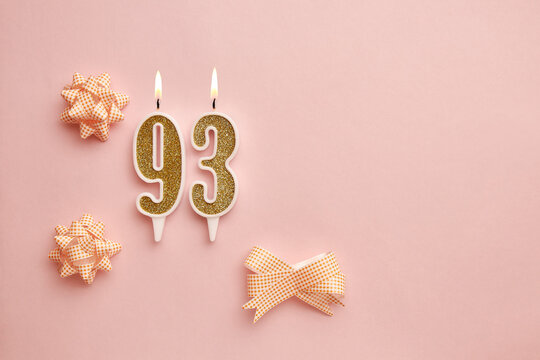 Candles with the number 93 on a pastel pink background with festive decor. Happy birthday candles. The concept of celebrating a birthday, anniversary, important date, holiday. Copy space. banner