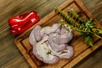 Cow bowels presented on a wooden board with ingredients, ready to grill