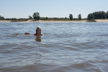 A young girl swimming in a river on a hot summers day during the summer vacation