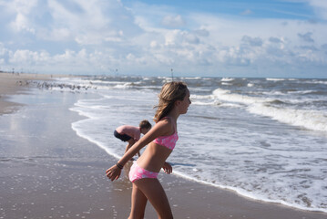Naklejka premium A young boy and girl playing in the waves of the sea during a warm day during a summer vacation.