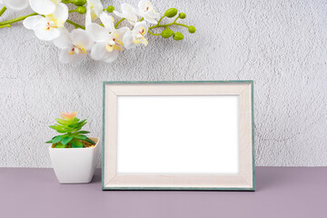 The blank photo frame and white orchid flower on cement wall, with copy space and clipping path for the inside.