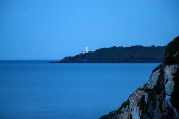 Towards Start Point Lighthouse at sunset.  A calm still sea on a cool summer evening.  The lighthouse guiding mariners.
