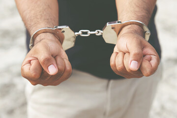 Prisoner male criminal standing in handcuffs with hands behind back. banner copy space.
