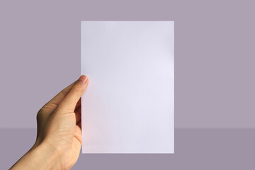 Fototapeta premium Realistic hand holding A5 paper mockup. Portrait A5 international paper size mockup. Simple, clean, modern, minimal paper mock up. Paper mockup in hand