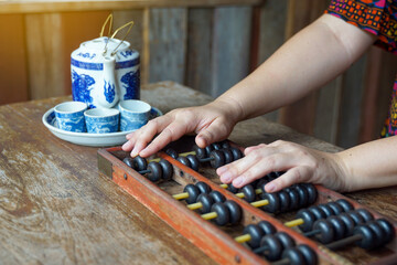 On the desk of an ancient Chinese shop It consists of an abacus for calculating product prices and a teacup set for sipping tea while working. Soft and selective focus.  