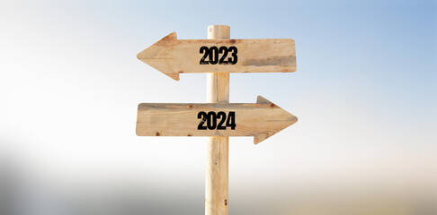 New year 2024 coming concept background photo. Wooden arrow shape sign board with 2023 and 2024 text on it.