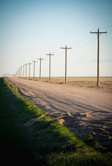 long country dirt road with phone poles