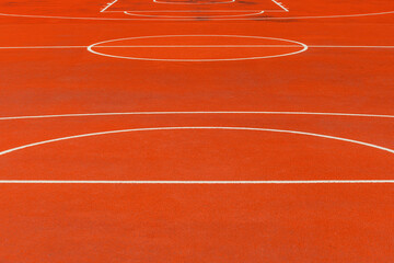 Minimalist abstract background of an orange tartan outdoor basketball court with white lines.