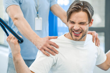 Fototapeta premium Young man having na physical therapy with instructor in the rehabilitation center