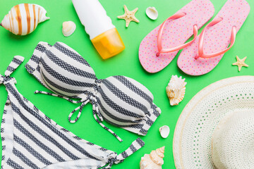 Woman swimwear and beach accessories flat lay top view on colored background Summer travel concept. bikini swimsuit, straw hat and seasheels. Copy space Top view
