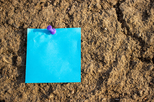 purple map pin blue square paper note on brown dried mud with empty free space for template or blank copy area 