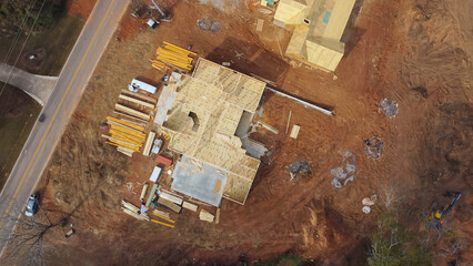Nightly degree aerial view construction site of two wooden houses in envelope and frame truss, joist, beam, plank on concrete slab foundation in suburban area of Flowery Branch, Georgia, USA