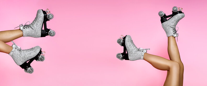 Close up photo of woman's body part. Legs wearing glamour silver glitter roller skates with shoelaces on pink vivid  background