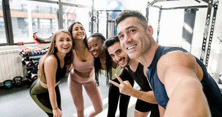Cheerful diverse sportspeople doing selfie at gym